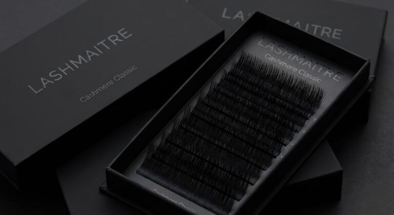 Professional product shot of LASHMAITRE "Cashmere Classic" lash trays in premium matte black packaging. Close-up view highlights the ultra-soft, non-shiny texture of the fibers, designed specifically for creating realistic classic natural eyelash extensions. Wholesale collection displayed.