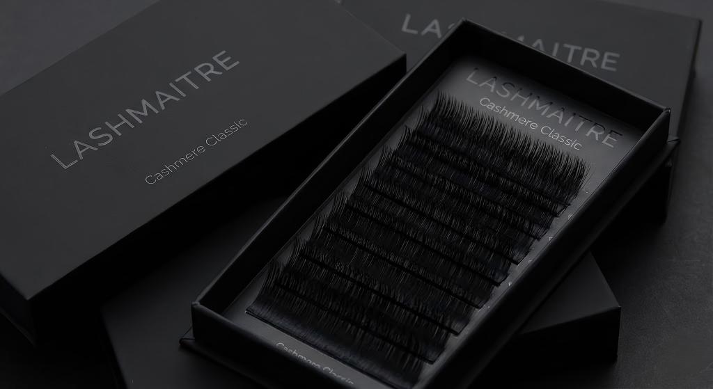 Professional product shot of LASHMAITRE "Cashmere Classic" lash trays in premium matte black packaging. Close-up view highlights the ultra-soft, non-shiny texture of the fibers, designed specifically for creating realistic classic natural eyelash extensions. Wholesale collection displayed.