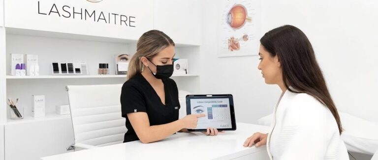 A professional LASHMAITRE artist consulting a client on Latisse compatibility with eyelash extensions, explaining safe application methods for growth serums to ensure lash health.