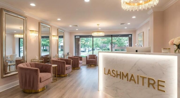Interior view of the luxurious LASHMAITRE salon, featuring pink velvet chairs, large golden mirrors, and a marble reception desk, now offering a special UVA student lash discount.