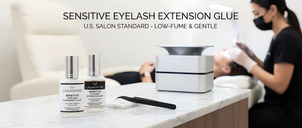 LASHMAITRE professional adhesive bottles labeled as sensitive eyelash extension glue displayed in a clean U.S. salon setting, designed for low-fume application.