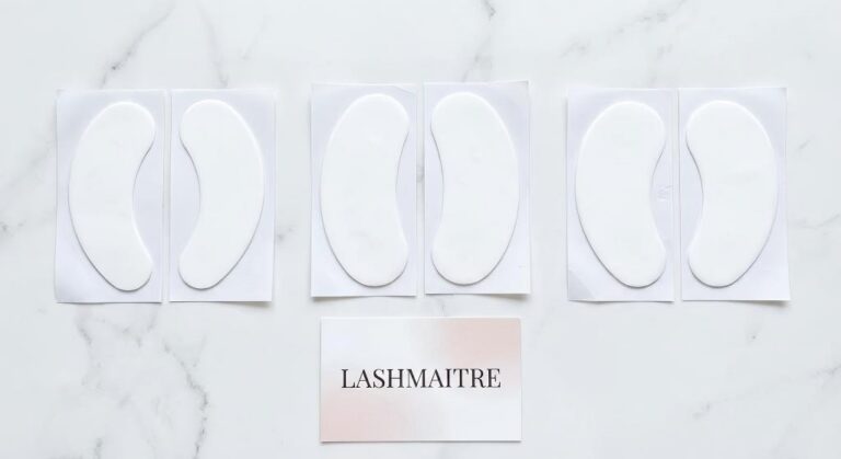 Display of banana, oval, and kidney-shaped eye patches for eyelash extensions laid out on a white surface next to a Lashmaitre brand card.