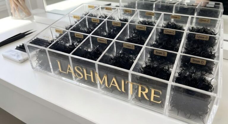 A clear acrylic storage organizer by LASHMAITRE, featuring multiple compartments filled with sorted loose fans eyelash extensions. Labels for C and D curl, ranging from 8mm to 12mm, are visible on each section, providing a perfect storage solution.