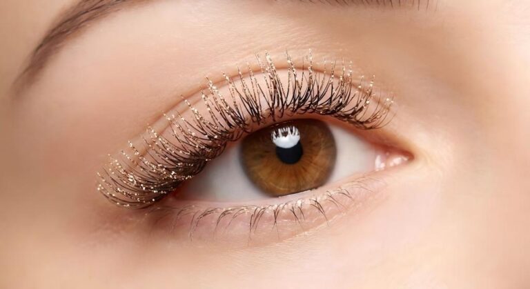 A macro photograph demonstrating the elegant styling of champagne glitter eyelash extensions suitable for everyday wear, showing subtle sparkle under studio light on a brown eye.