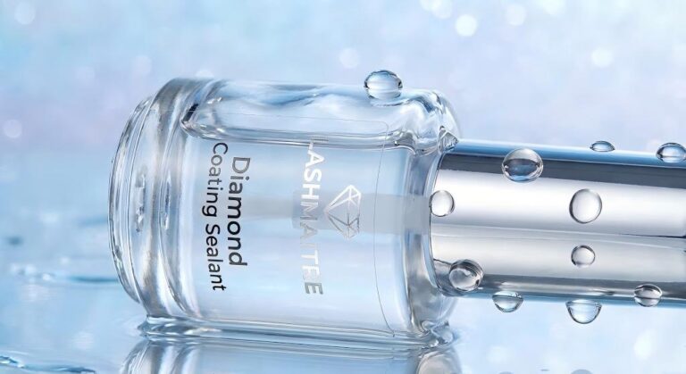 A close-up photograph of the LASHMAITRE Diamond Coating Sealant bottle resting on a wet, reflective surface. Water droplets are visibly beading and rolling off the glass and silver cap, illustrating the protective barrier it creates. This visual demonstrates why using sealant is the best way on how to prolong eyelash extensions by repelling moisture and oils.