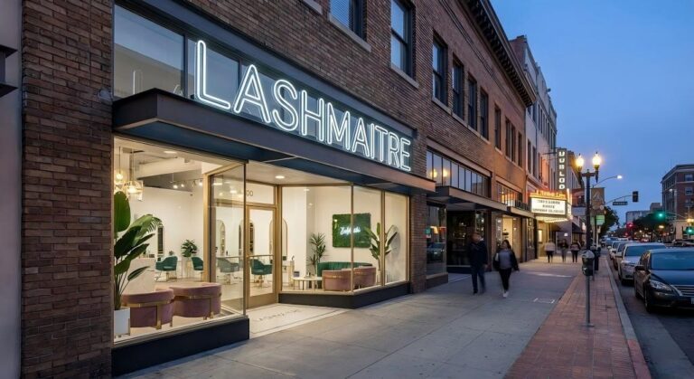A twilight view of the trendy LASHMAITRE storefront with a glowing neon sign, highlighting its modern location for eyelash extensions among Downtown Santa Ana (DTSA) businesses.