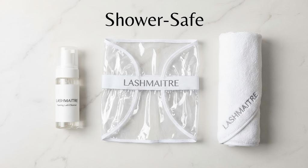 A flat lay of the LASHMAITRE 'Shower-Safe' retail kit, featuring a foaming cleanser, protective visor, and soft towel. This aftercare set provides the essential tools to answer "yes" to the question: can you shower with eyelash extensions?