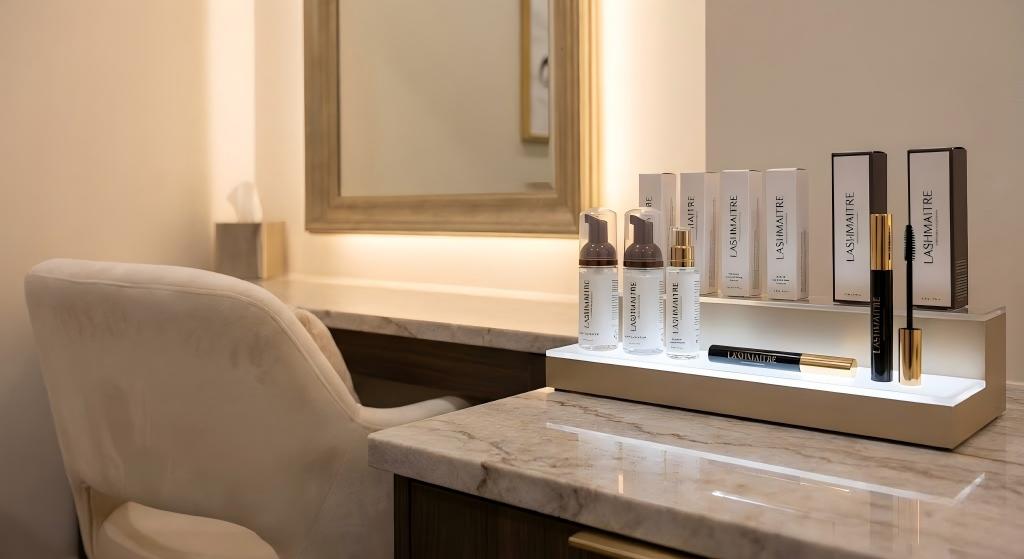 A luxury salon workstation in Ashburn featuring a sleek marble countertop displaying LASHMAITRE premium OEM private label retail products, including lash cleansers and serums, illuminated by soft ambient lighting.