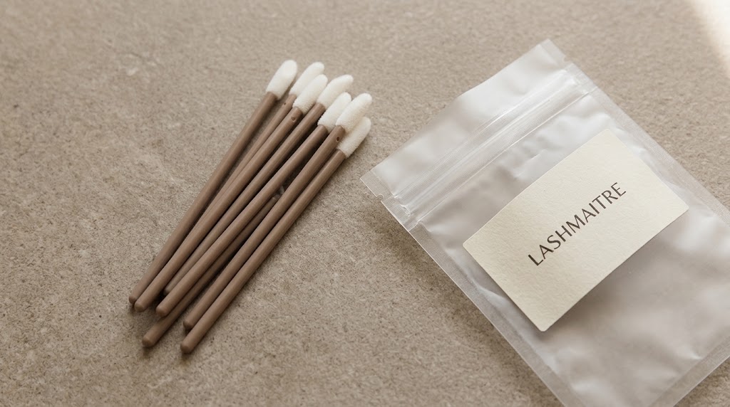 Flocked disposable lip applicators beside LASHMAITRE labeled sample packaging